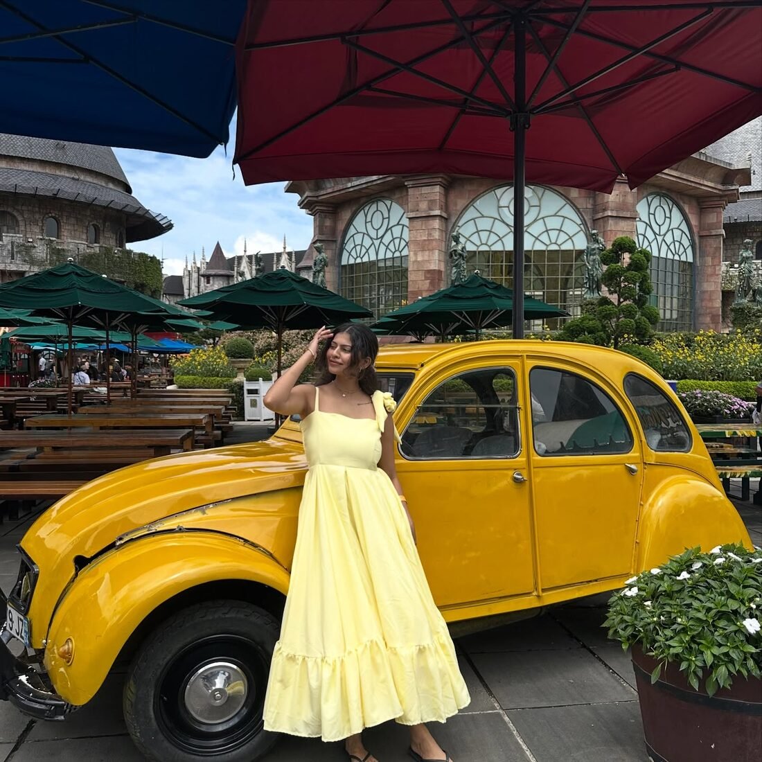 Shreya Jadhav in a yellow dress beside a vintage yellow car